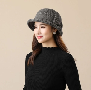Detail of grey houndstooth bucket hat with a bow accent and elegant rolled brim