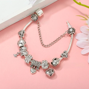 Detail of silver-plated snake chain bracelet with heart, bow, and crystal charms