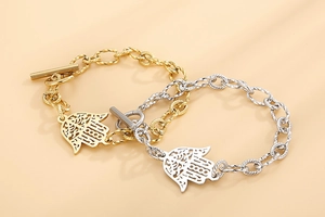 Détail des charms Main de Fatma sur bracelets à chaîne dorée et argentée avec fermoir