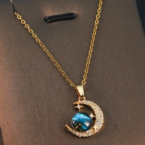 Detail of gold crescent moon necklace with blue celestial orb and sparkling crystals
