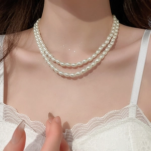 Close-up of elegant double-layered pearl necklace on neck with dewy skin and lace detail