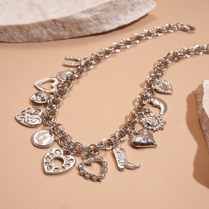 Detail showing silver charms like cowboy boots and hearts on layered metal chain necklace
