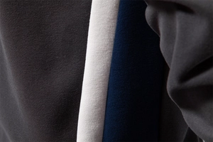 Macro detail of the tricolor patchwork knit fabric in dark grey, white and navy blue