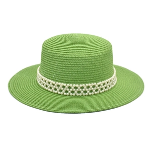 Detail of light green woven boater hat featuring elegant pearl mesh ribbon and fine texture