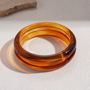 Close-up of amber acrylic resin bangle with irregular marbled texture on stone base