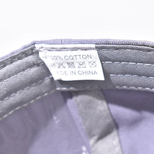 Detail view of cotton washing label and stitching on purple baseball cap interior