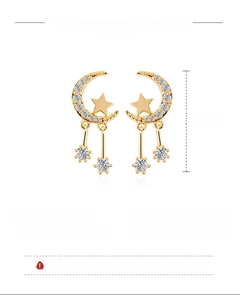 Detail view of gold celestial earrings with moon star charms and 925 silver needle post