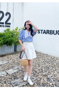 Outdoor lifestyle shot of a light brown quilted crossbody bag with embroidered ribbon strap
