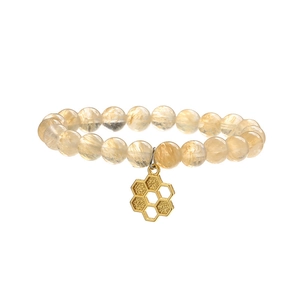 Bracelet en perles de quartz œil de tigre avec pendentif nid d'abeille doré sur fond blanc