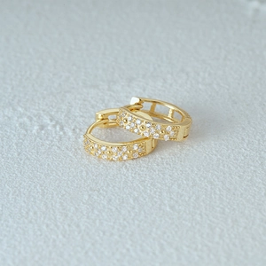 Detailed close-up of golden S925 sterling silver hoop earrings with clear zircon stones