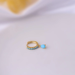 Detail of gold ear cuff featuring turquoise beads and a teardrop pendant earring