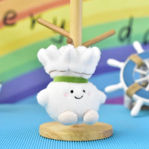 Close-up of a cute cartoon shuttlecock plush charm with a smiling face on a wooden stand