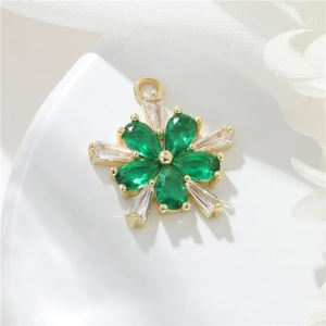Macro detail of a 14k gold plated flower pendant with green stones and white crystals