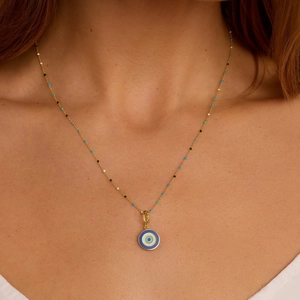 Macro shot of gold Evil Eye coin necklace with colorful beads on female neck
