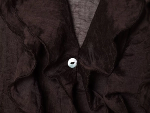 Macro shot of dark layered ruffles and textured fabric with a small shell button detail