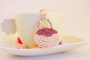 Detail of gold handbag keychain featuring pink rhinestones and white pearls with ring
