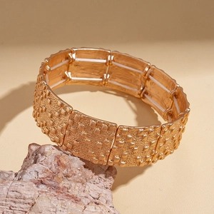 Détail d'un bracelet extensible en métal doré avec des motifs de carrés en relief