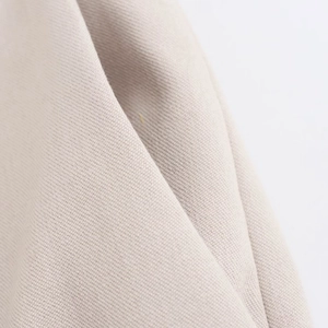 Detailed macro view of soft beige knit fabric texture and premium draped wide leg trousers