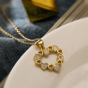 Elegant gold heart pendant necklace featuring sparkling zircon stones on a white surface