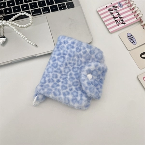 Blaue Plüschtasche mit Leopardenmuster, Druckknopf und Herzanhänger auf dem Tisch