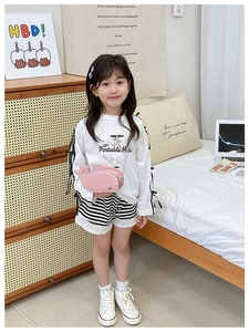 Pink dolphin-shaped kids crossbody bag with metal chain strap worn by a model