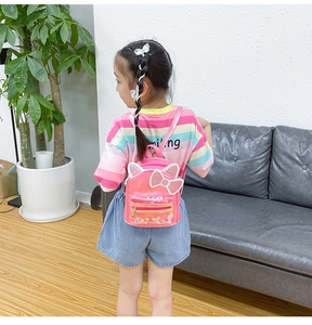 Rear view of a girl wearing a pink glittery mini backpack with cat ears and bow detail