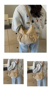 Detail of khaki nylon pleated crossbody bag showing drawstring texture and adjustable strap