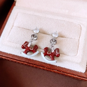 Macro shot of rocking horse earrings with red and white enamel and zircon accents