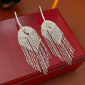 Vue macro de boucles d'oreilles pompons argentées avec strass sur boîte en bois