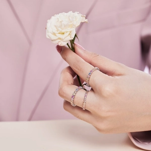 Detail of stacked S925 silver rings with colorful zircons and a white rose accent