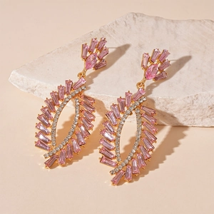 Macro detail of leaf-shaped earrings with pink rhinestones and gold-tone finish
