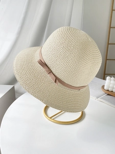 Detailed texture of woven straw sun hat with elegant dusty pink ribbon and bow
