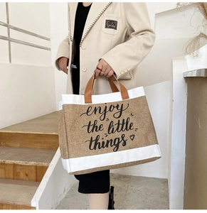 Detail of jute tote bag with enjoy the little things script and brown leather handles