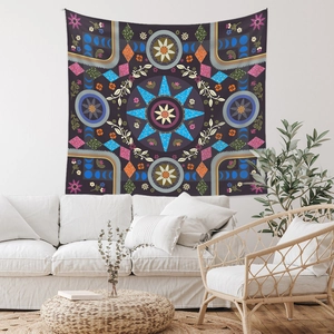 Modern bohemian mandala tapestry in dark purple and blue tones on white wall above sofa