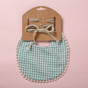 Détail d'un bavoir bébé à carreaux verts avec ensemble de bandeaux à nœuds assortis