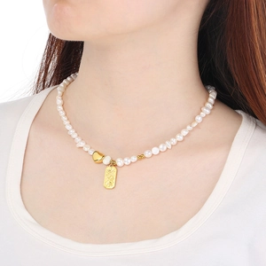 Detail of French-style pearl necklace with heart and rectangle charms on a model neck