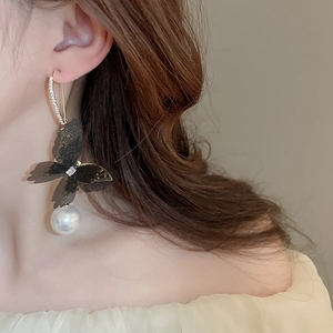 Detail of elegant mesh butterfly earrings with pearl drop and crystal gold hooks