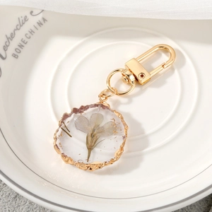 Detail of handmade resin keychain featuring purple dried flowers and gold leaf accents