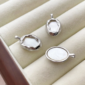 Close-up of three irregular oval silver pendants with white mother of pearl inlay