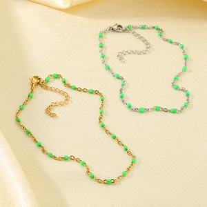 Detail of gold and silver anklets with green enamel beads on elegant beige silk fabric