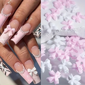 DIY nail art charms featuring pink and white resin bows with pearls for manicures