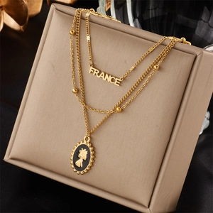 Close-up of double-layered gold necklace with France pendant and oval cameo charm