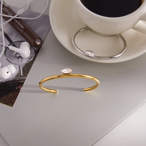 Detail of minimalist open C-shaped stainless steel bracelets in gold and silver finish