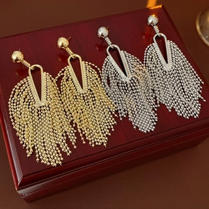 Detail of gold and silver geometric triangle earrings with delicate beaded tassel chains