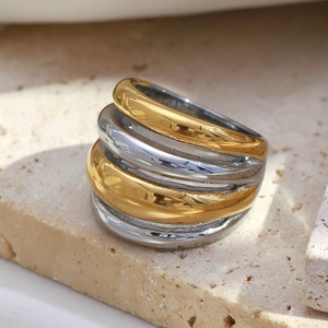 Macro shot of two-tone layered stainless steel ring on beige stone base