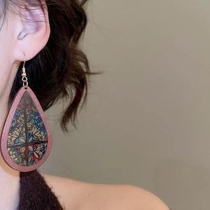 Detailed close-up of a teardrop wood earring with colorful floral bohemian patterns