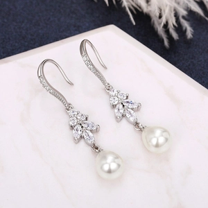 Macro detail of long silver drop earrings with white pearls and sparkling cubic zirconia