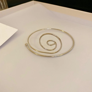 Detalle de un elegante brazalete de espiral plateado con acabado de metal pulido liso