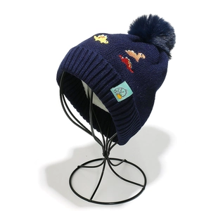 Detailed knit texture of dark blue dinosaur embroidery hat with a large pompom