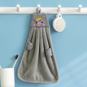 Grey coral fleece pig shaped hand towel with yellow crown and wave edges hanging on wall